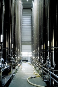Industrial stainless steel holding tanks rest on a monolithic floor coating system.