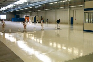 Contractors work diligently applying a concrete seal coating to a warehouse floor.