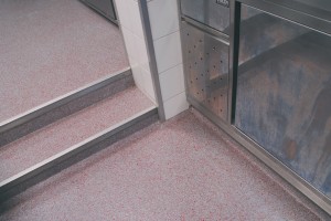 Commercial seamless floor displayed in bathroom with two small steps and shower area.