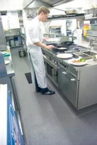 A commercial kitchen floor is depicted with chef prepping the requirements for the day.