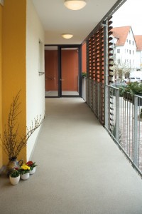 A concrete surface takes on the appearance of natural river rock in exterior hallway of commercial building.