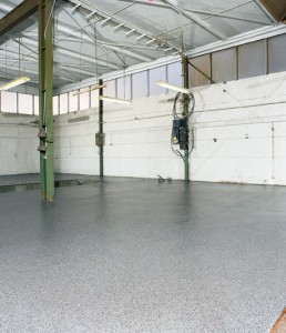 Industrial garage depicted displaying new concrete coating extending from garage to driveway.