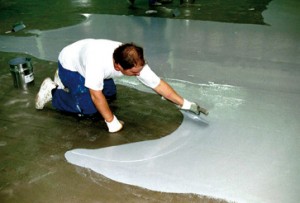 A flooring compound for self leveling is spread evening across a concrete floor by a certified installer.