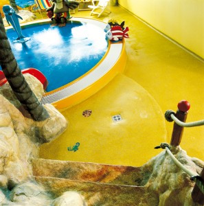 A bright yellow indoor poured rubber playground surface enriches this interior space.