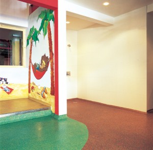 A multi colored rubber poured playground surface brightens this interior daycare play area.