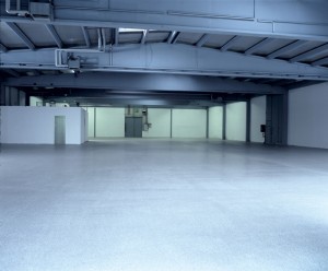 Large empty floor plan glows blue with specified poured hangar surface coating design.