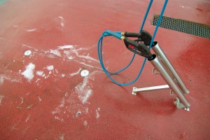 A heavy duty pressure washer rests atop red material floor.
