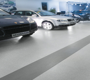 Cars atop multi colored large stripe flooring shine brightly in dealership.