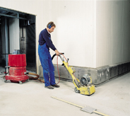 Professional flooring installer works large concrete resurfacing machine.