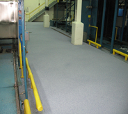 Newly resurfaced concrete shines bright with grey coating in large industrial access walkway.