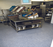Deli worker preps food on grey floor.