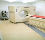 A hospitals x-ray machine sits center of cream yellow colored flooring room.
