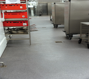 Multiple floor drains adourn grey coated industrialed kitchen.