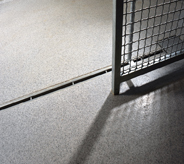 Sliding jailed gate casts shadow across light grey floor system.