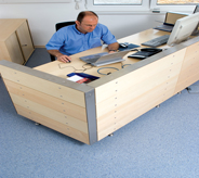 An office desk sits on top of a blue floor in a small room.