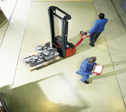 Commercial warehouse floorings displays resiliency as workers move heavy material with a pallet jack.