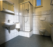Full industrial bathroom area displays tiled walls meeting dark grey no slip flooring coating design.