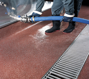 Worker hooks up hose to the tank that is on a solvent resistant floor.