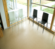 Open glass surrounds waiting room allowing sun light across area seating floor coating that is UV protected.