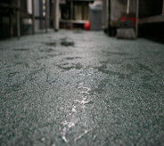 Floor view of beaded water atop ash colored waterproof flooring system.