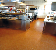Kitchen area with orange cafeteria flooring.
