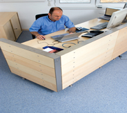 Cars dealership employee sits atop desk area flooring.