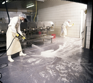 Clean room flooring being pressure washed by worker.