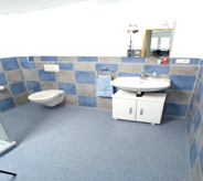 Quaint commercial setting extends into bathroom area flooring surrounded by matching checker board tiled walls.