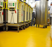 Worker pushes cart across bright yellow concourse area floor.