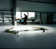 Car lift rests center while mechanic in foreground stands atop durable garage floor system.