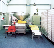 Cheese processer sits center with a large wall of stacked crates covering left side of floor.