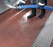 Man holding tank hose in on wet flooring in milk production area.