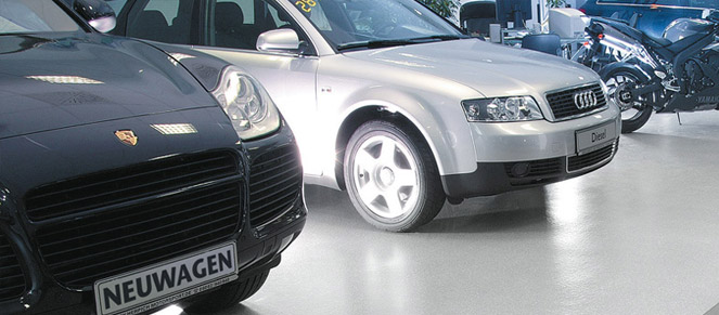 Cars parked on a dealership gray single color floor.