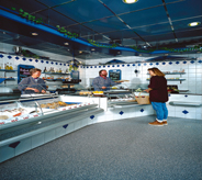 A grocery store shopper stands on flake floor while selecting meat for dinner.