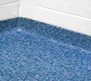 Close view of institutional room corner showing seamless design as floor system continues virtically up wall replacing traditional cove base.