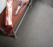 Meat rests atop cutting board and clean grey processing floor.