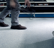 Patron wearing heavy boots walks across grey colored nonskid flooring surface.