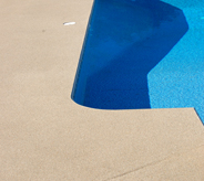 This poured floor pool deck looks vibrant against the bright blue water.