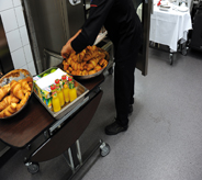 A restaurants catering table sits atop cool grey floor coating while waiter distributes dishes.