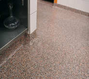 Corner of a rock river flooring design displays seamless quality with floor system working as cove base protectant.