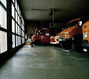 Heavy duty parked trucks occupy seamlessly clean interior garaged flooring real estate.