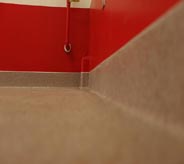 A beige seamless floor is accented by a bright red wall.