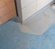 Tiled flooring seamlessly meets poured acrylic flooring both coated with slip resistance sealer.