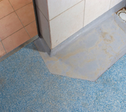 Tiled flooring seamlessly meets poured acrylic flooring both coated with slip resistance sealer.