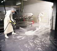 Worker pressure washes solvent resistant floor.