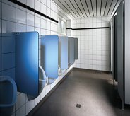 Urination stalls in commercial bathroom depict high resist floor coat in deep grey color.